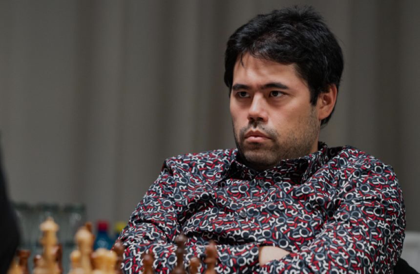 Hikaru Nakamura sėdi prie šachmatų lentos 