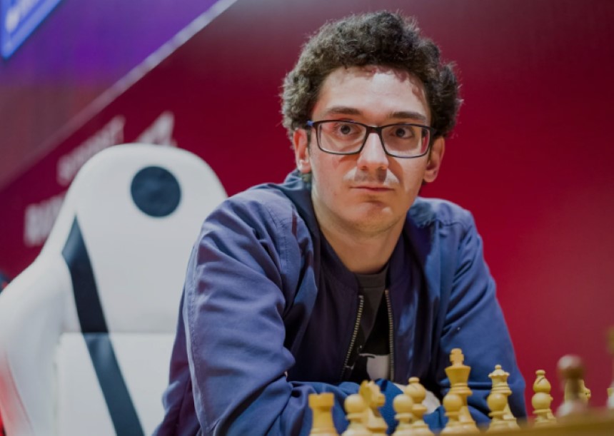 Fabiano Caruana sėdi prie šachmatų lentos 