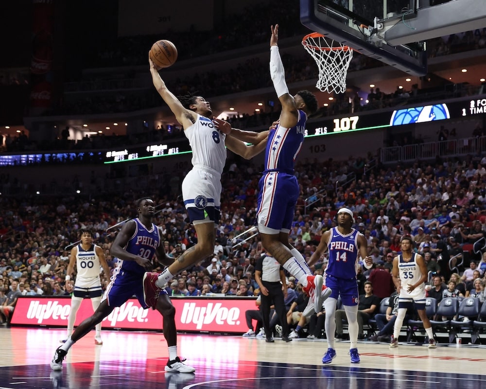 Timberwolves žaidėjas deda į krepšį per Filadelfijos žaidėjus 